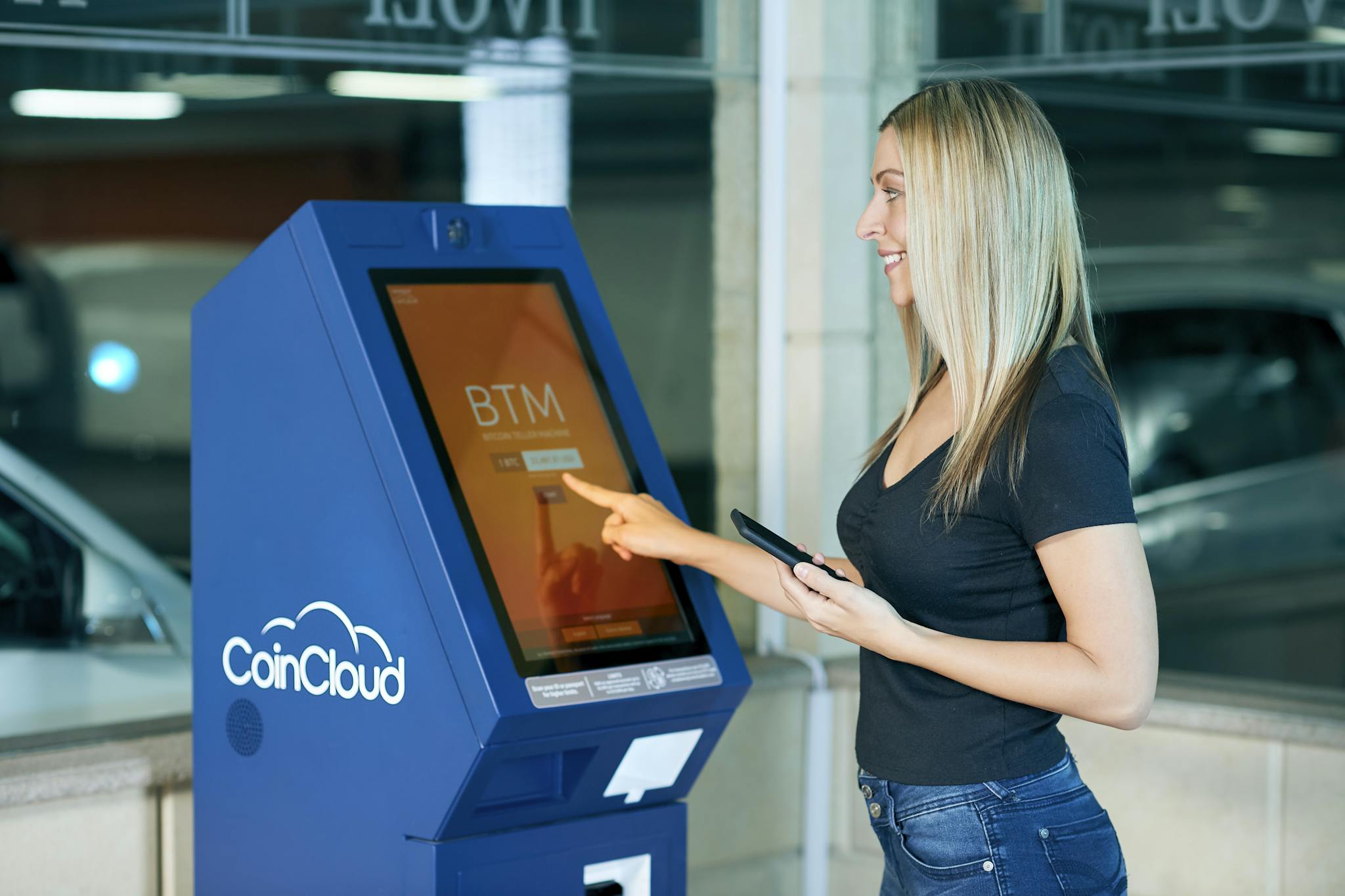 A woman interacts with a CoinCloud machine indoors, showcasing modern digital banking.